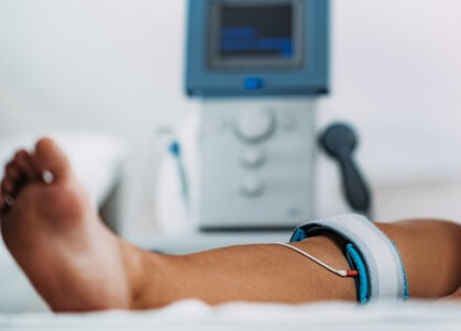 TENS, Transcutaneous Electrical Nerve Stimulation in Physical Therapy. Therapist Positioning Electrodes onto Patient's Knee in Bozeman