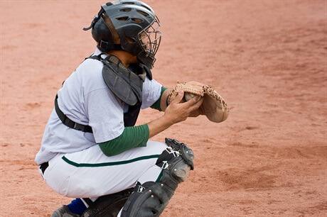Baseball catcher in green and white in relation to sports injuries