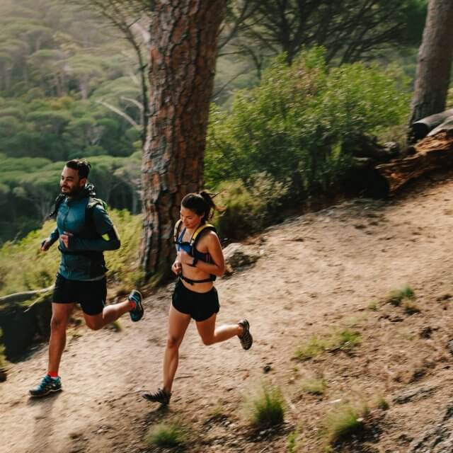 A man and woman trail running in the woods